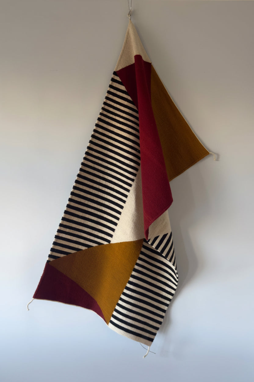 Handmade wool rugs with geometric pattern in black,, red, white and okra color  hanging on the wall