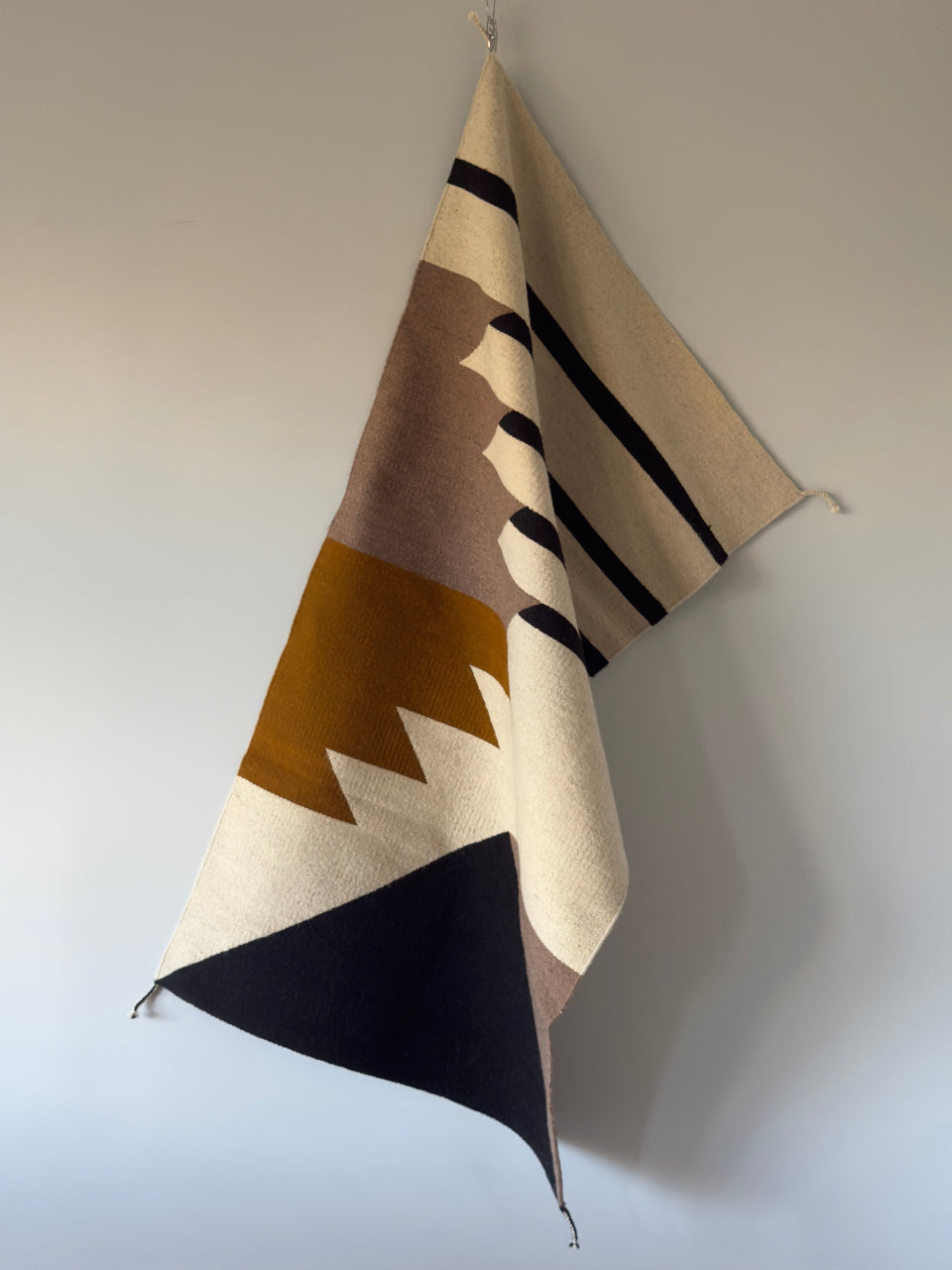 Handmade wool rugs with geometric pattern in black, brown, white and okra color. Rug made in Oaxaca, Mexico by Zapotec weavers. Rug Hanging on the wall