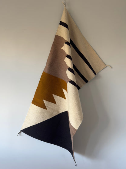 Handmade wool rugs with geometric pattern in black, brown, white and okra color. Rug made in Oaxaca, Mexico by Zapotec weavers. Rug Hanging on the wall