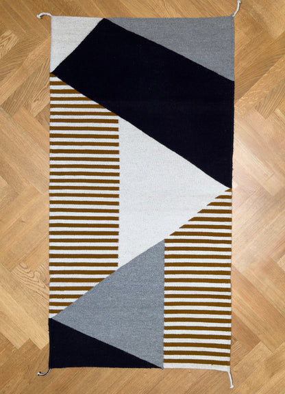 Picture of handmade wool rug with geometric pattern in black, gray, white and okra color. Rug made in Oaxaca, Mexico by Zapotec weavers. 