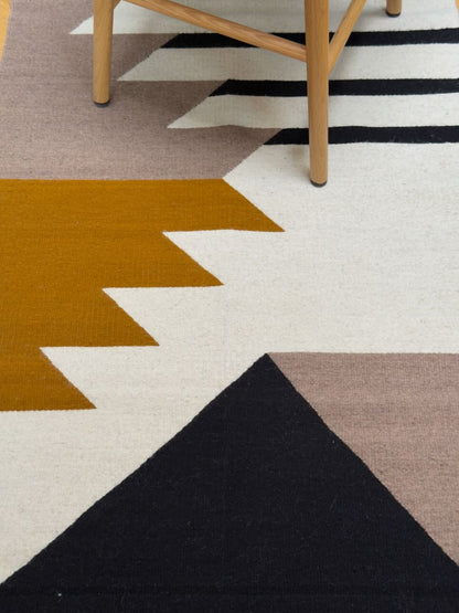 Detail of Handmade wool rugs with geometric pattern in black, brown, white and okra color. Rug made in Oaxaca, Mexico by Zapotec weavers. 