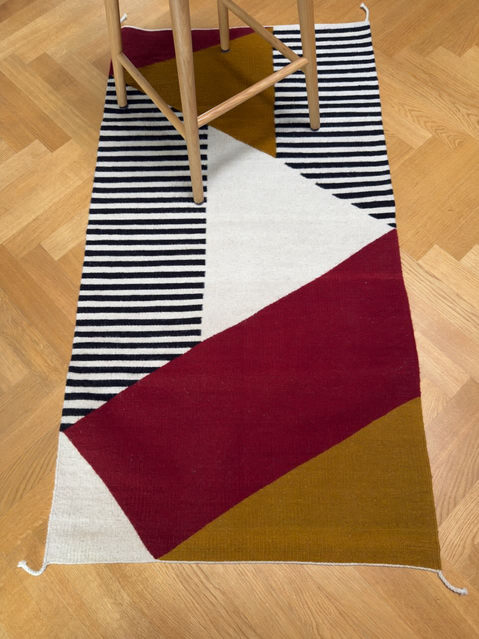 Handmade wool rugs with geometric pattern in black,, red, white and okra color on the floor.. Rug made in Oaxaca, Mexico by Zapotec weavers. 