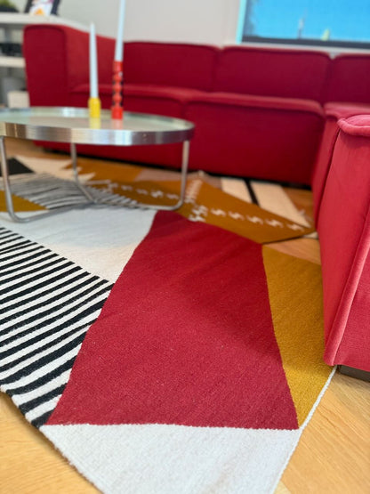 Handmade wool rugs with geometric pattern in black,, red, white and okra color in living room.. Rug made in Oaxaca, Mexico by Zapotec weavers. 