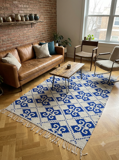 Living room with a blue and white patterned rug, beige sofa, and wooden furniture. Handmade wool rug using natural and Indigo dyed wool. made by hand by Zapotec in Oaxaca, Mexico
